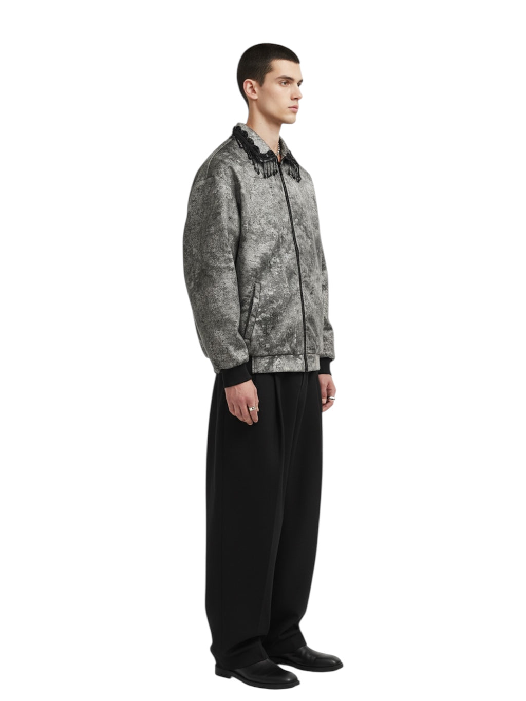 Man wearing a patterned jacket and black pants on a white background