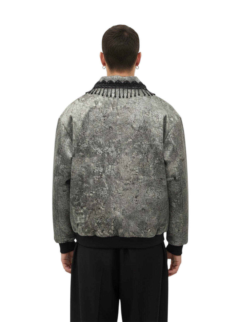 Person wearing a patterned jacket with fringe details on a white background