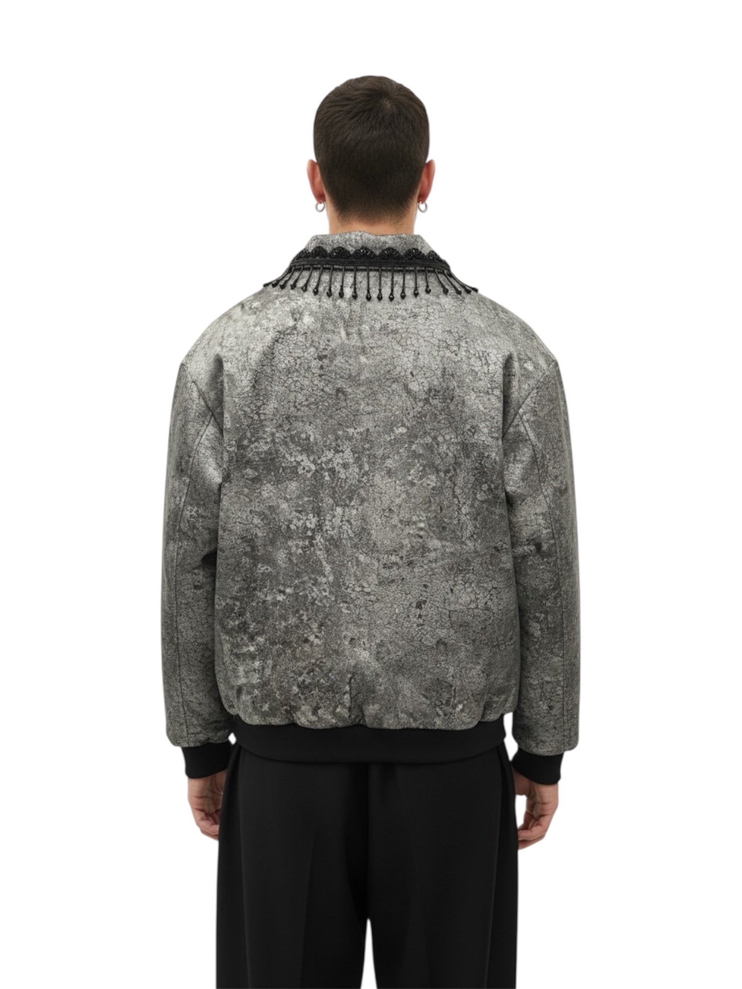 Person wearing a patterned jacket with fringe details on a white background